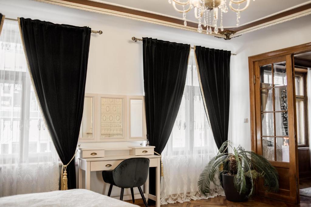 Schlafzimmer mit schwarzen Vorhängen, einem Schreibtisch und einem Kronleuchter in der Unterkunft Concert Hall boutique apartment in Cēsis