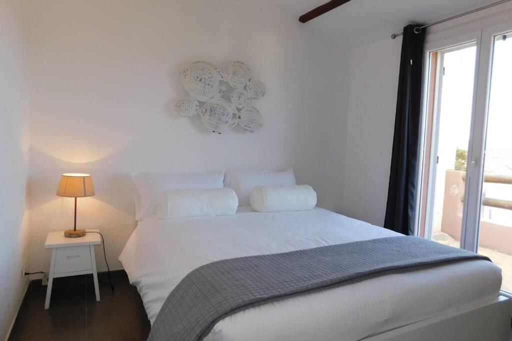 a white bedroom with a bed and a window at MINI VILLA SANTA GIULIA in Porto-Vecchio