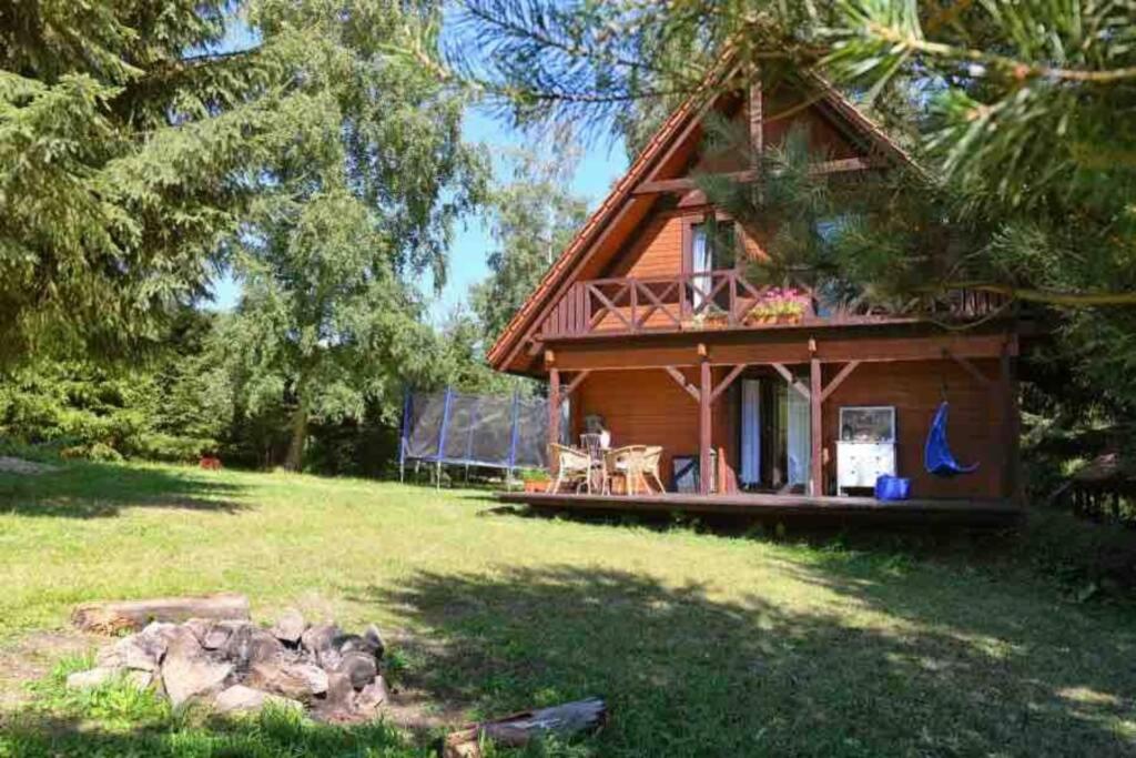 a small cabin with a porch and a grass yard at Nad strumykiem in Jugowice