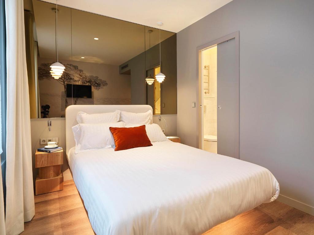 a bedroom with a large white bed with a red pillow at Le Katorze Hôtel in Paris
