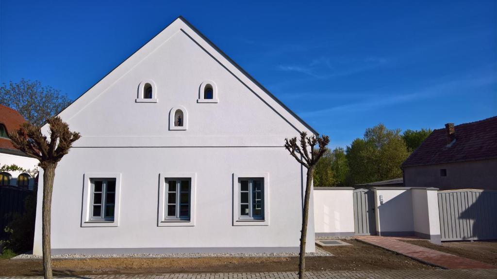 Biały dom z dwoma drzewami przed nim w obiekcie Rozália Vendégház 2 w mieście Sarród