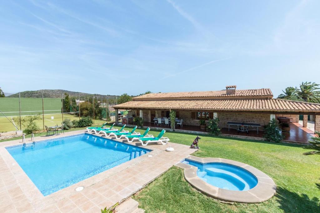 einen Pool mit Stühlen und ein Haus in der Unterkunft Villa Antonia in Pollença