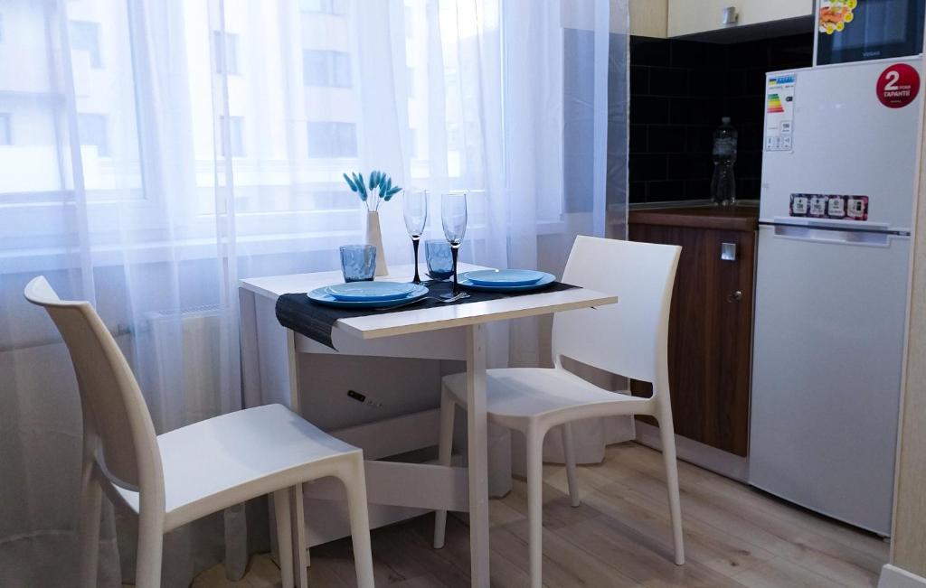 una piccola cucina con tavolo, sedie e frigorifero di Комфортная студия на Южном вокзале a Charkiv