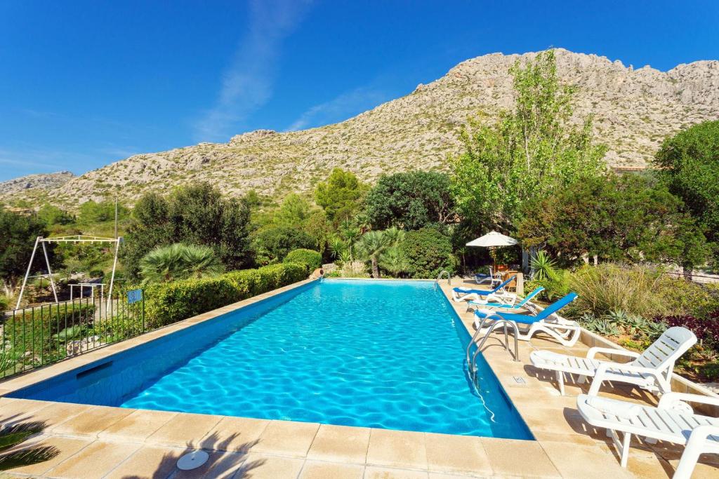 a swimming pool with chairs and a mountain in the background at Villa Piedra in Port de Pollensa