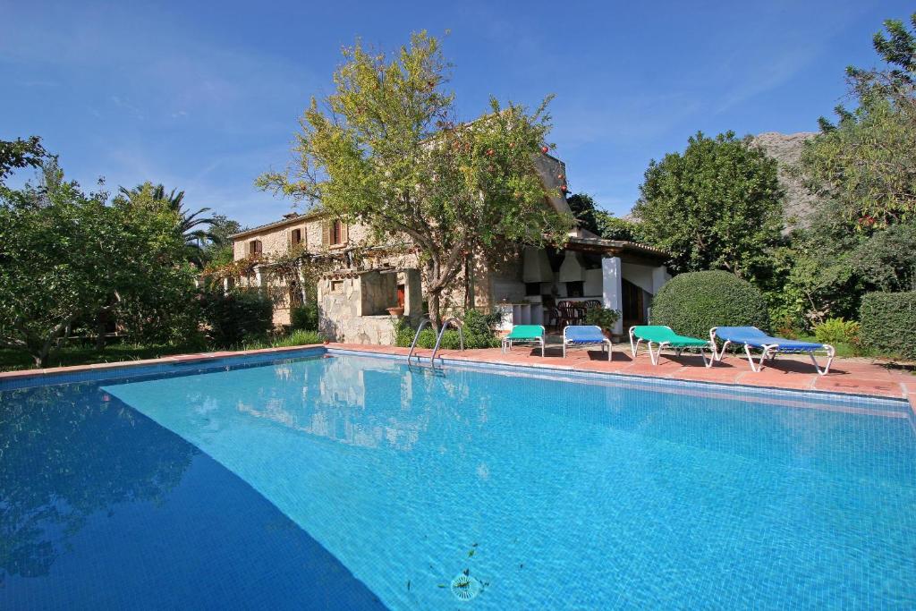 a swimming pool with two blue chairs and a house at Villa Punxa in Pollença