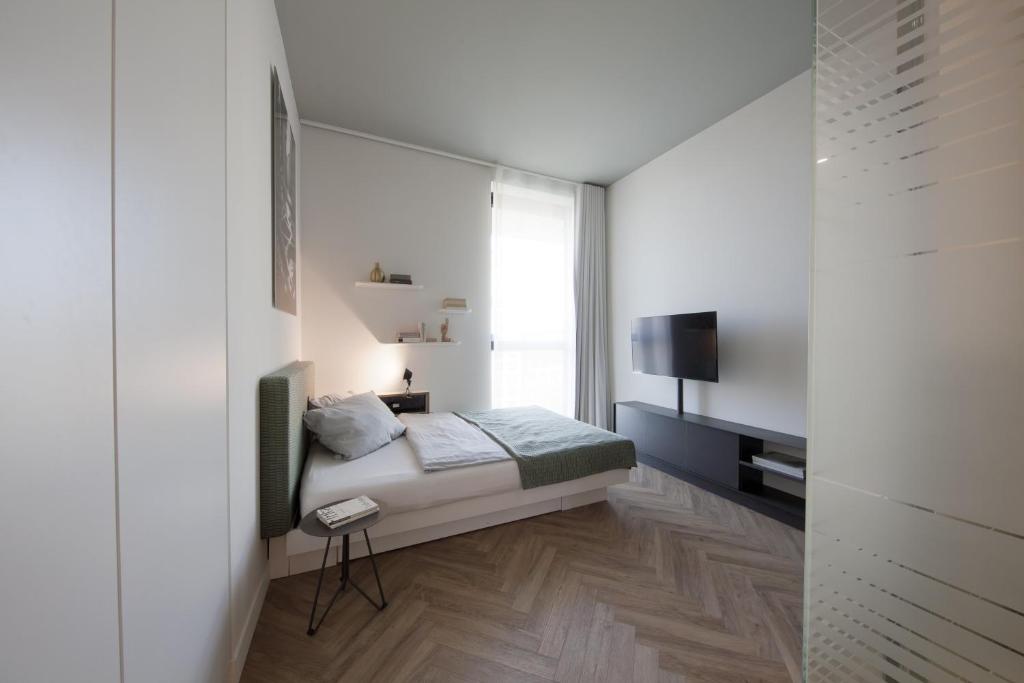 um pequeno quarto com uma cama e uma janela em smartments München Parkstadt Schwabing em Munique