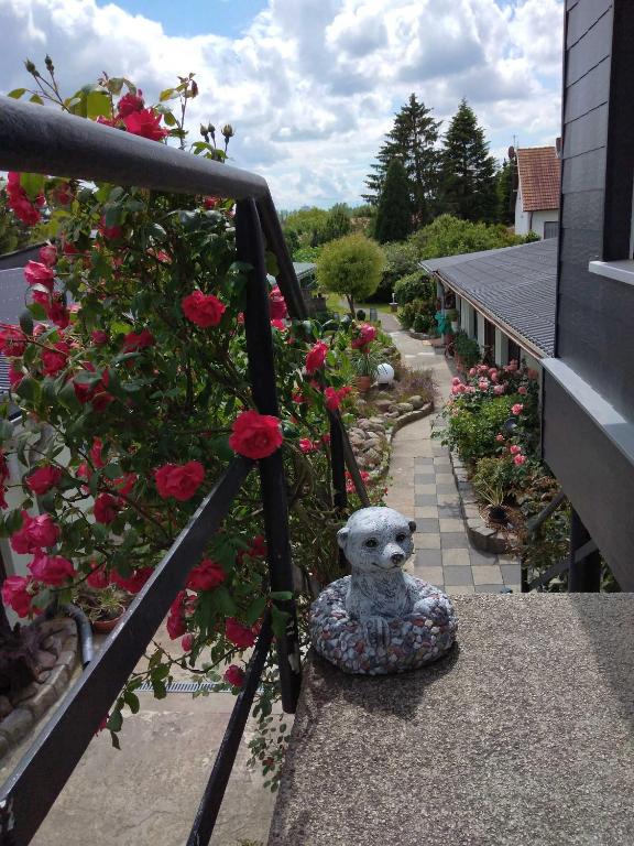 a statue of a dog sitting on a balcony with roses at Ferienbungalow 2 in Dierkow