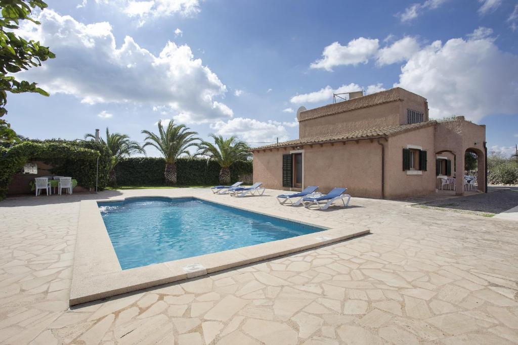 a swimming pool with two chairs and a house at Villa Servera in Santanyi