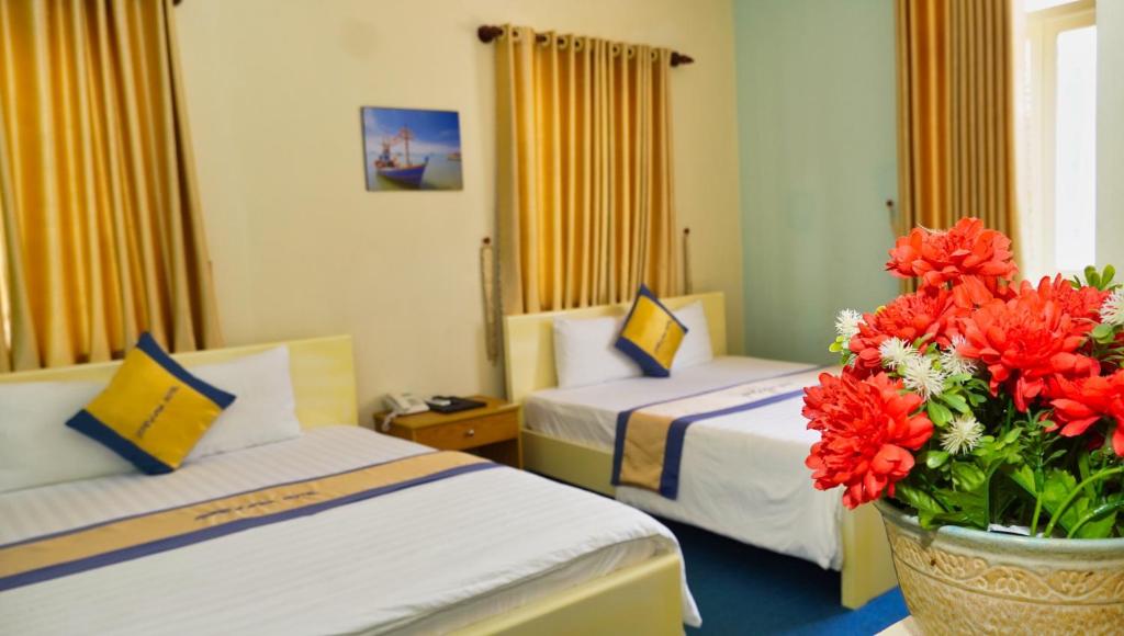 a hotel room with two beds and a vase of flowers at Rita Hotel in Vung Tau