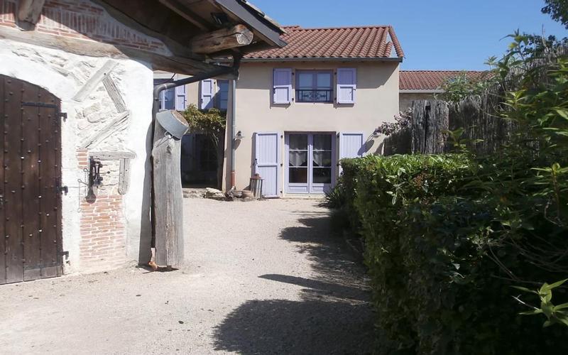 een wit huis met een poort en een gebouw bij GITE DU ROY D'AMONT (Plaine de l'Ain) in Lagnieu