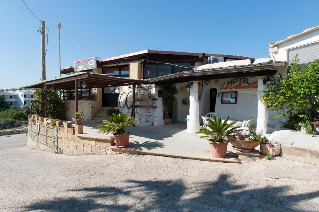 a building with potted plants in front of it at Hotel La Collinetta in Morciano di Leuca