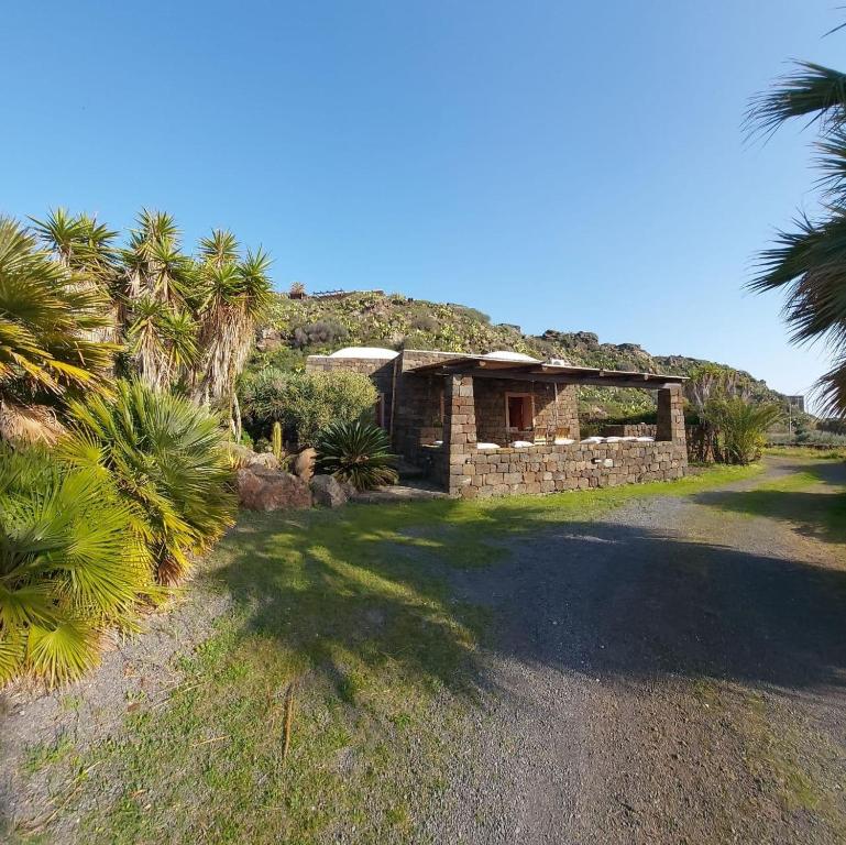 una casa in pietra con palme e un edificio di Agricola Pineda a Pantelleria