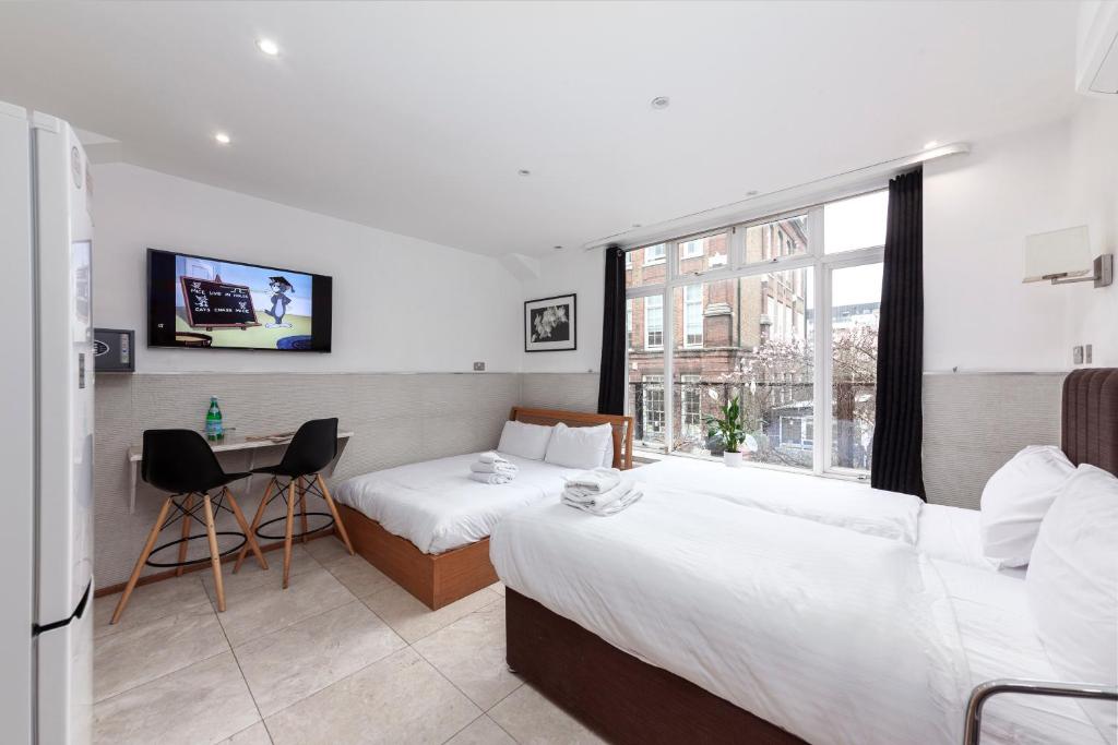 Pokój hotelowy z 2 łóżkami i biurkiem w obiekcie Argyle Apart Hotel w Londynie
