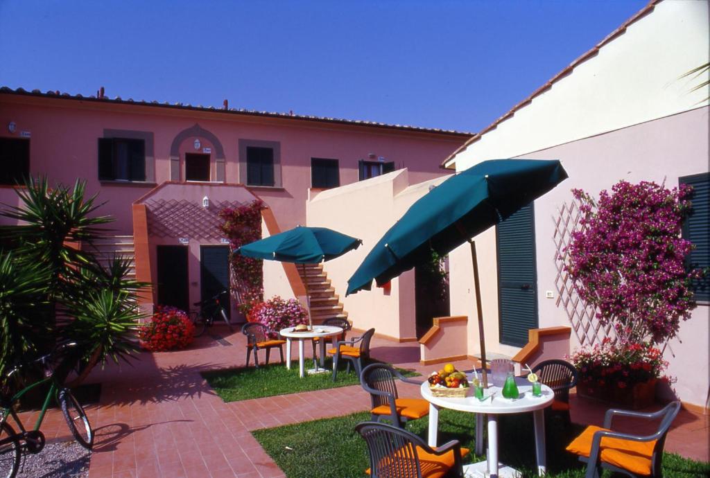 un patio con tavoli, sedie e ombrelloni di RESIDENCE TERME ISOLA D'ELBA SRL a Portoferraio