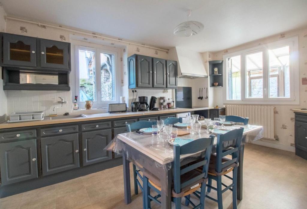 a kitchen with a table with blue chairs in it at Les Planchettes in Orcival