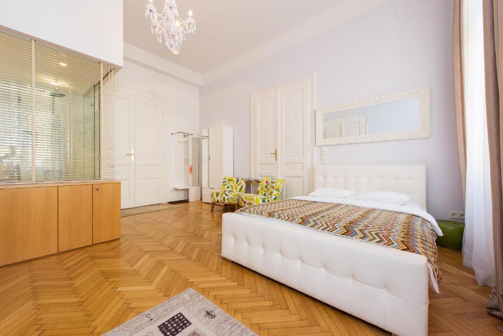 biała sypialnia z łóżkiem i żyrandolem w obiekcie Rosa Linde - Comfort Rooms w Wiedniu