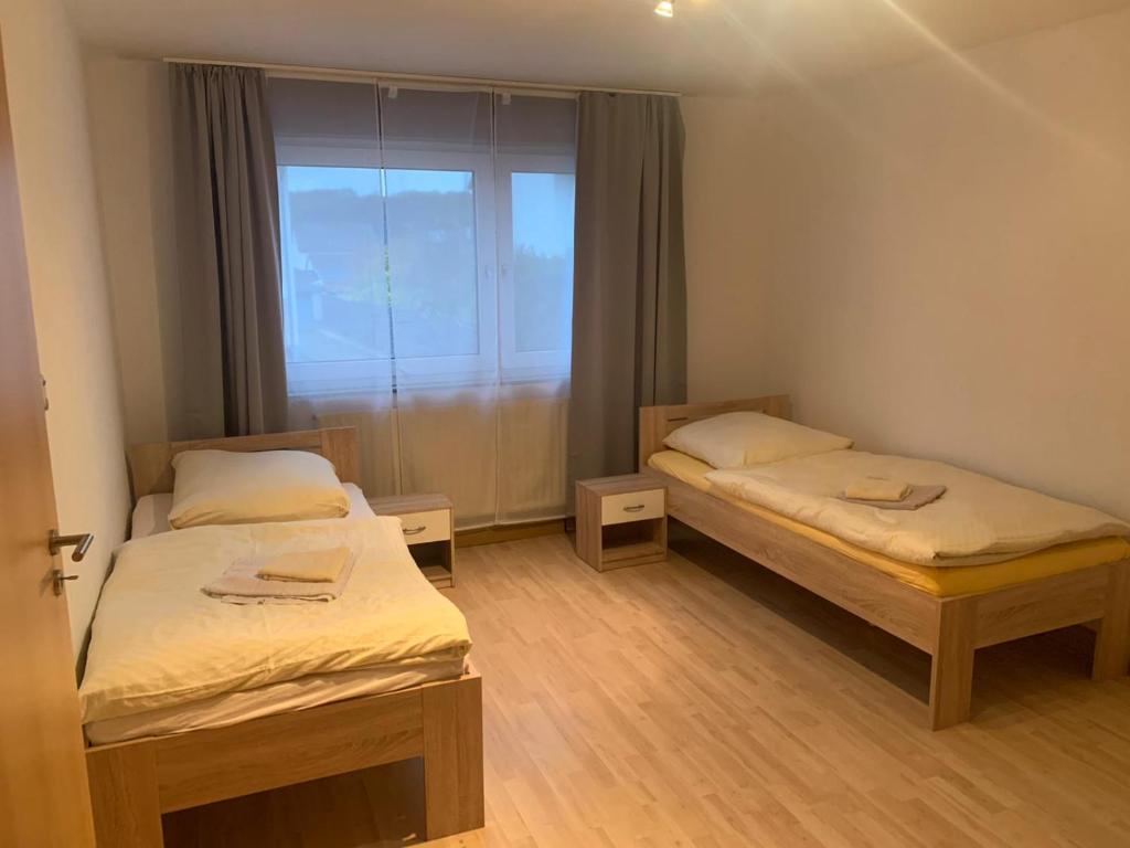 two beds in a small room with a window at Monteurwohnung Göllheim in Göllheim