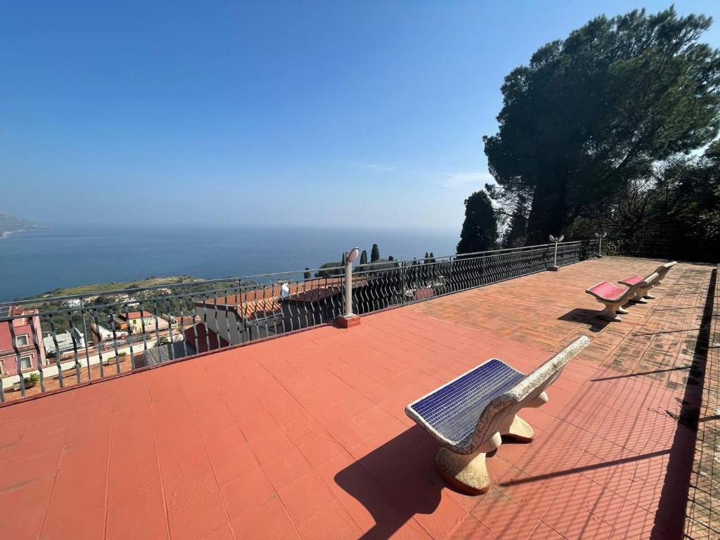 a group of benches sitting on top of a brick patio at Appartamento Taormina vista mare in Taormina