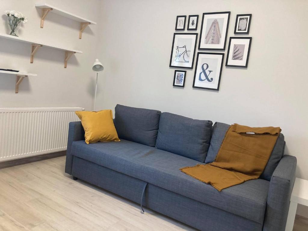 een blauwe bank in een woonkamer met foto's aan de muur bij Apartament Prusa in Lublin