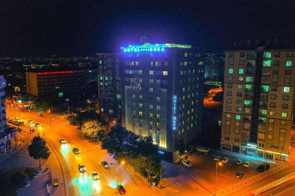 ein hohes Gebäude mit blauem Schild oben in der Nacht in der Unterkunft Bera Konya Hotel in Konya