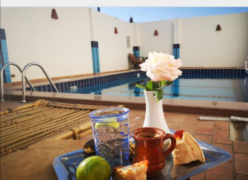 Sinderella Private Pool Villa في الأقصر: طاولة مع مزهرية مع وردة وخبز ومزهرية مع