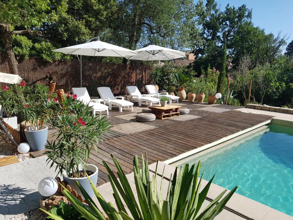 einen Hinterhof mit einem Pool mit Stühlen und einem Sonnenschirm in der Unterkunft Mas Provençal au Cannet des Maures in Le Cannet-des-Maures