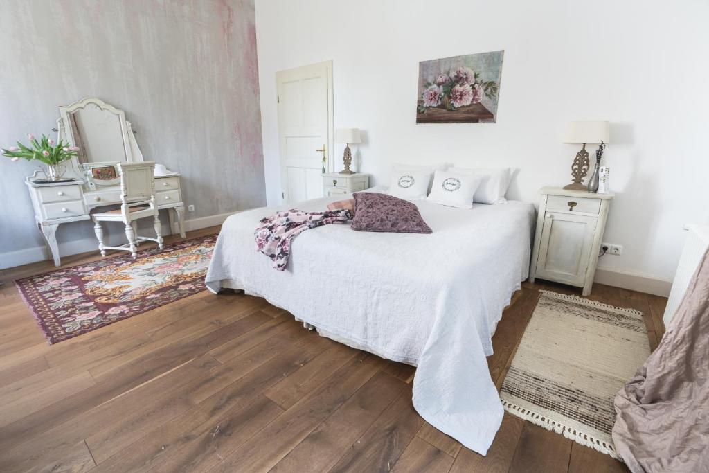 een slaapkamer met een wit bed en een spiegel bij Babérliget Kúria - Adults only in Polány