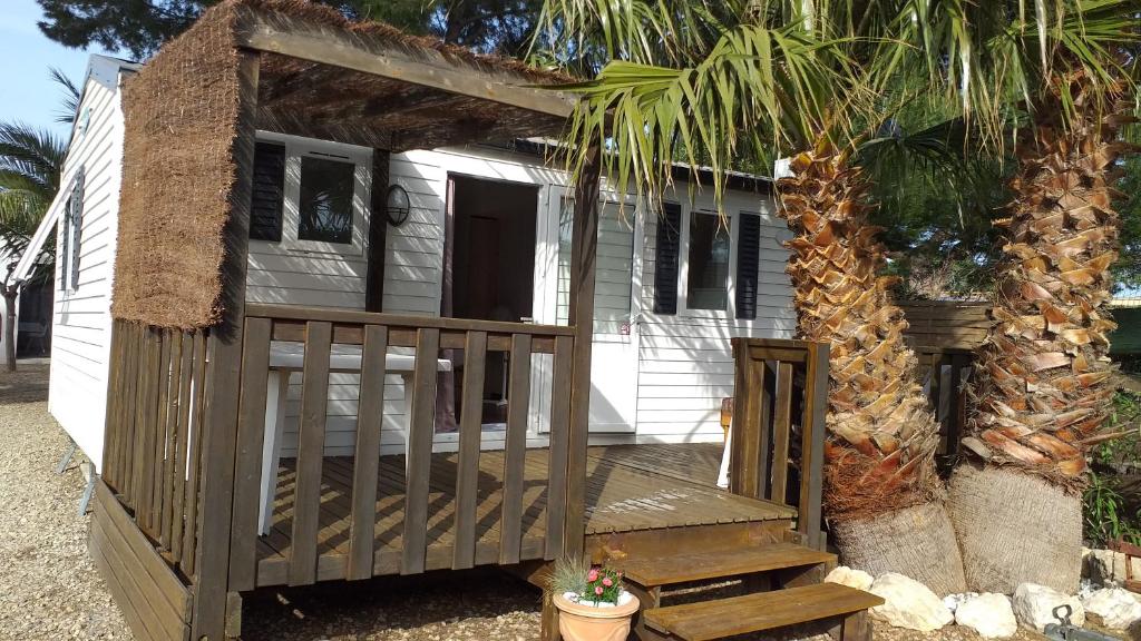 Cette petite maison dispose d'une terrasse couverte en bois et d'un escalier. dans l'établissement Mobilhome chez Cathy & Simon, à Marseillan