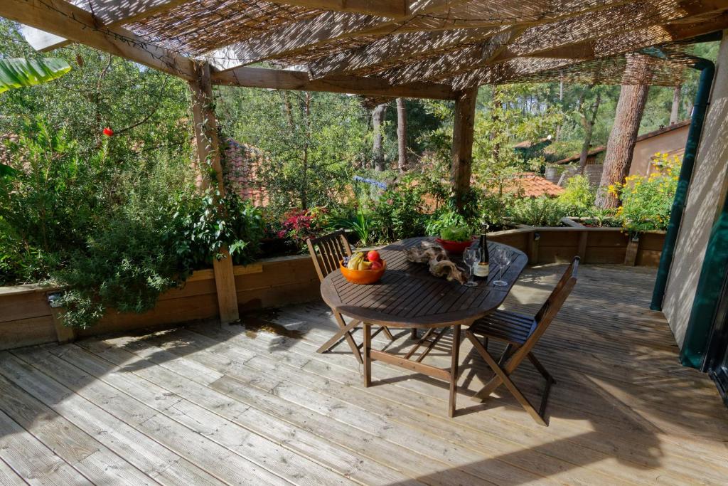 un patio avec une table et des chaises sous une pergola dans l'établissement Villa sous les pins de Moliets, à Moliets-et-Maa