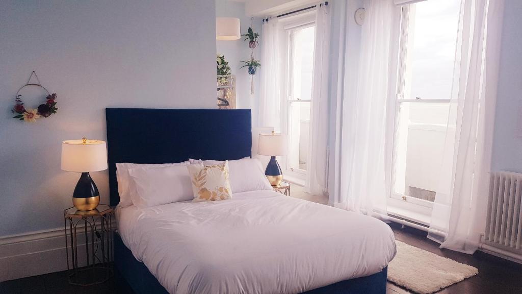 a bedroom with a bed with a blue headboard and two windows at The Bank Hotel & Bistro in Hastings