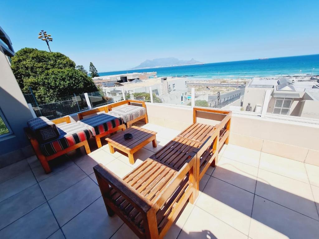 a balcony with benches and a view of the beach at 2WhiteWaters Bloubergstrand Homestay in Bloubergstrand