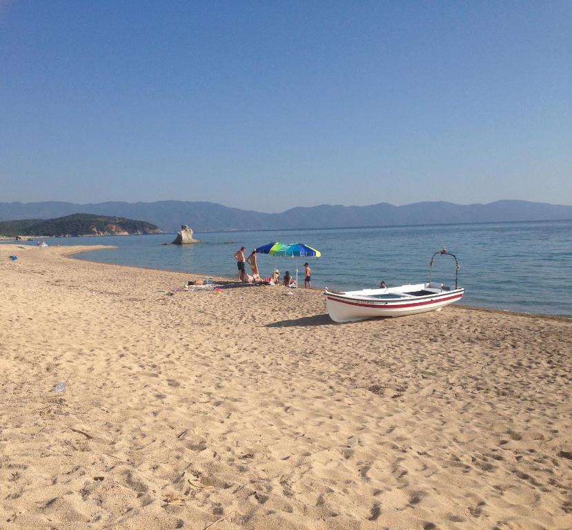 a boat on a beach with people on the water at Ikidiki Beach Villa in Ierissos