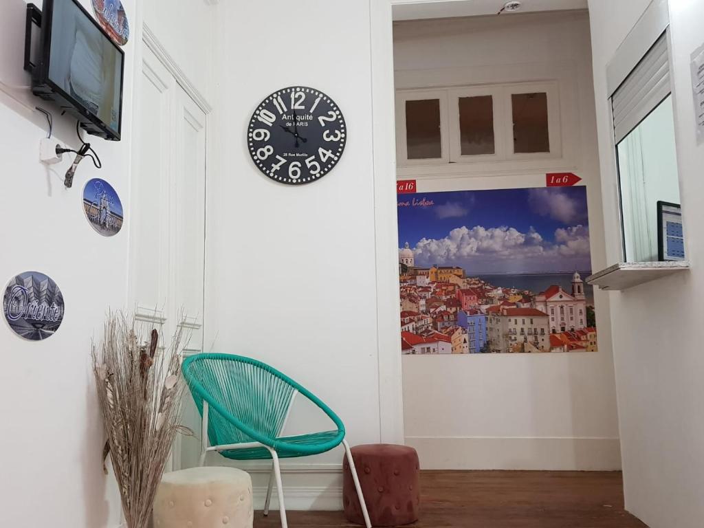 a room with a green chair and a clock on the wall at 7 Luz Hostel in Lisbon