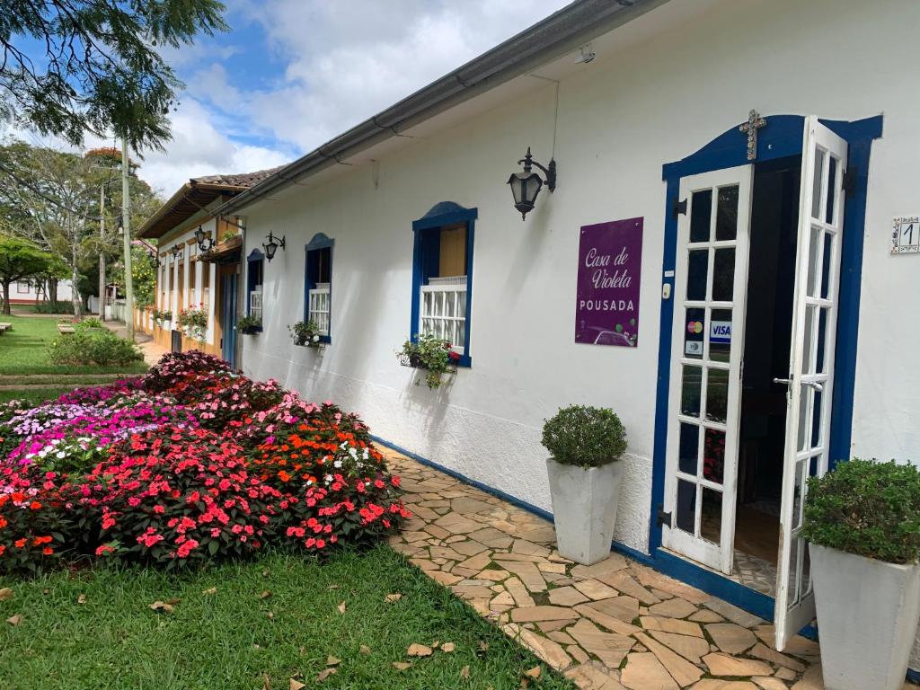 Un bâtiment blanc avec des fleurs devant lui dans l'établissement Casa de Violeta Pousada, à Tiradentes