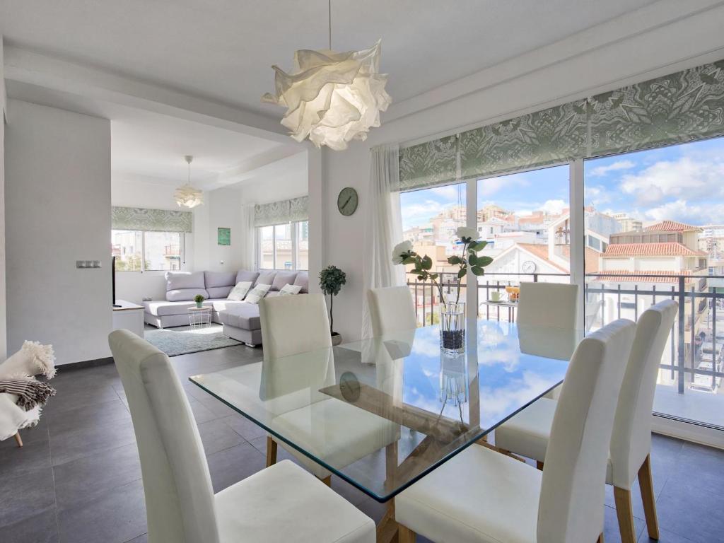 salon ze szklanym stołem i białymi krzesłami w obiekcie Sur Suites El Carmen w mieście Fuengirola