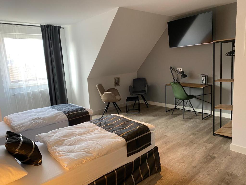 a bedroom with two beds and a desk and chairs at Aparthotel Charlotten in Hannover