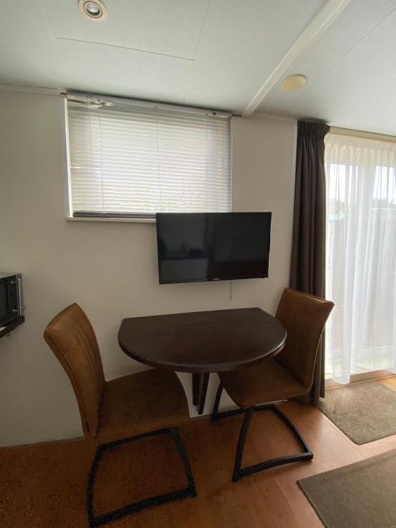 Zimmer mit einem Tisch, Stühlen und einem TV in der Unterkunft Studio de Aankomst in De Koog