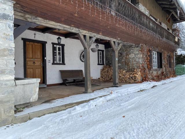 eine Veranda eines Gebäudes mit einer Bank im Schnee in der Unterkunft THE NEST in Les Gets