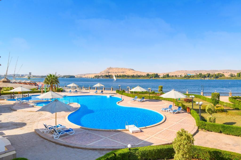 a pool with chairs and umbrellas next to the water at Tolip Aswan Hotel in Aswan