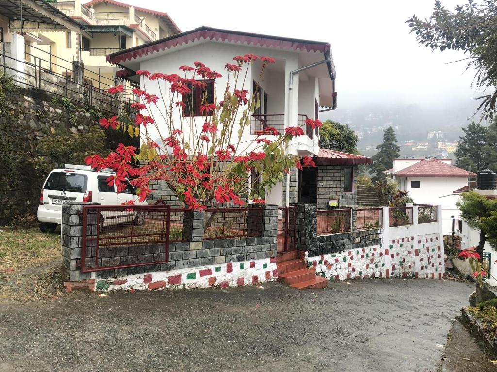 White house in Nainital في بهيمتال: منزل عليه زهور حمراء
