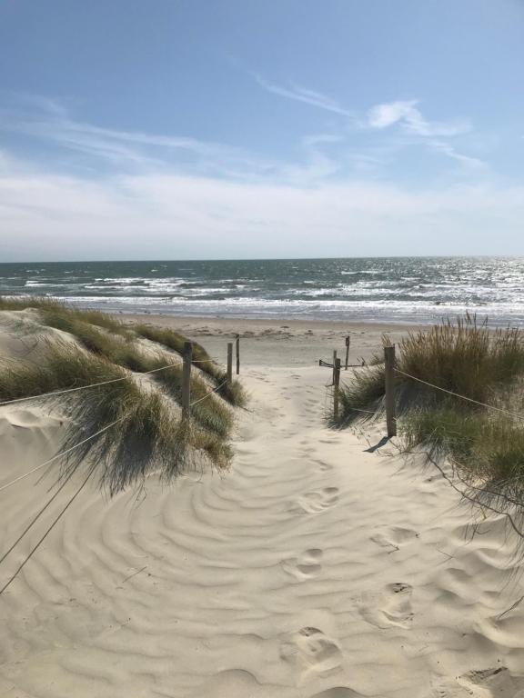 a sandy beach with footprints in the sand and the ocean at Linden House in West Wittering