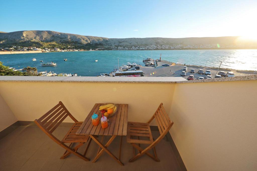 a table and two chairs on a balcony with a marina at Apartmani "Jadran" in Pag