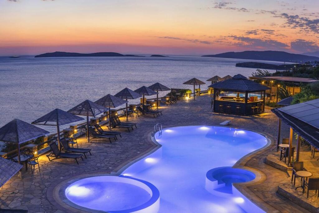 a resort with a swimming pool and the ocean at sunset at Blue Bay Resort Village in Batsi