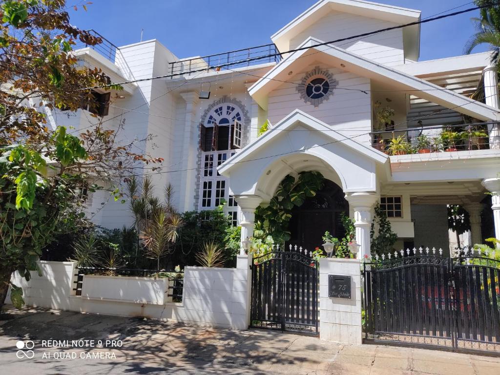 a white house with a black gate at Abode in Bangalore