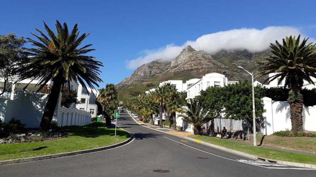 an empty street in front of a mountain with palm trees at Capevistas High Cape in Cape Town