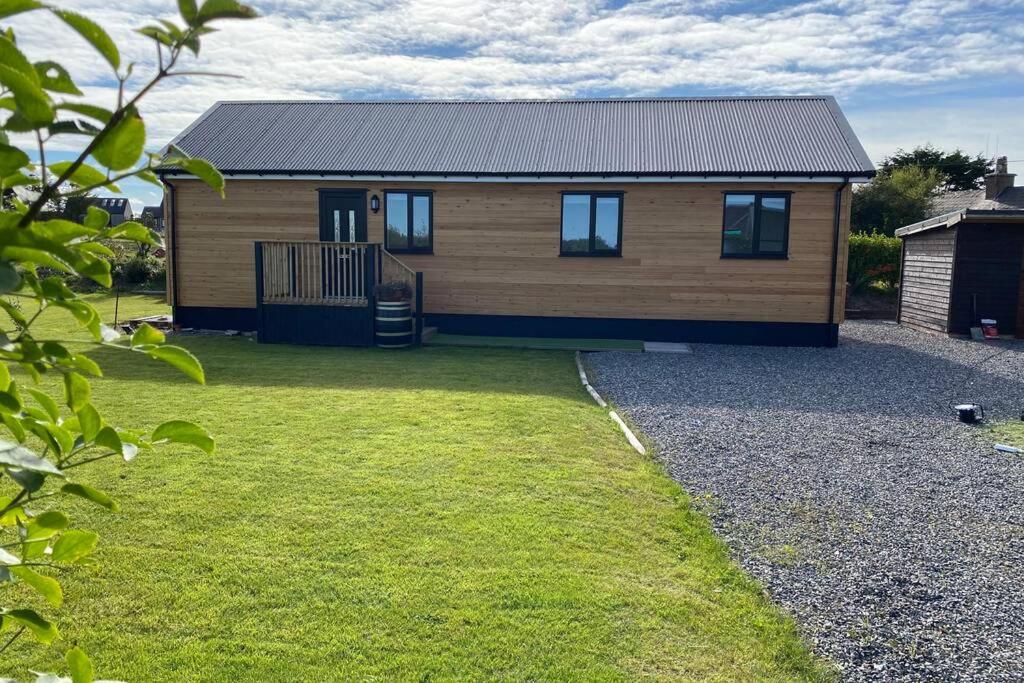 una pequeña casa de madera con un patio de césped en The Gallafield, Self Catering Bungalow , Stornoway, en Stornoway