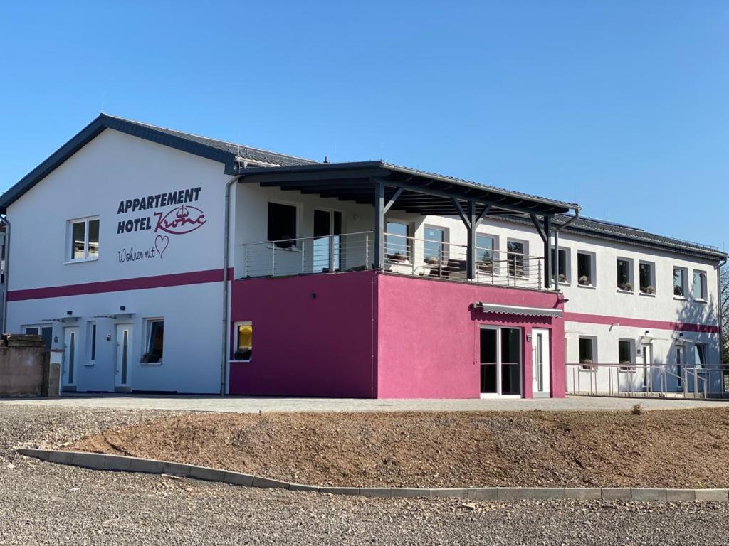 a white and pink building on the side of a road at Apartmenthaus Krone Wohnen mit Herz in Bexbach