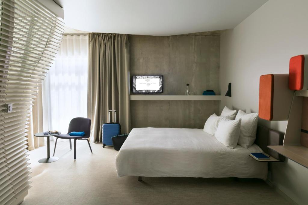 a hotel room with a bed and a chair at Okko Hotels Strasbourg Centre in Strasbourg