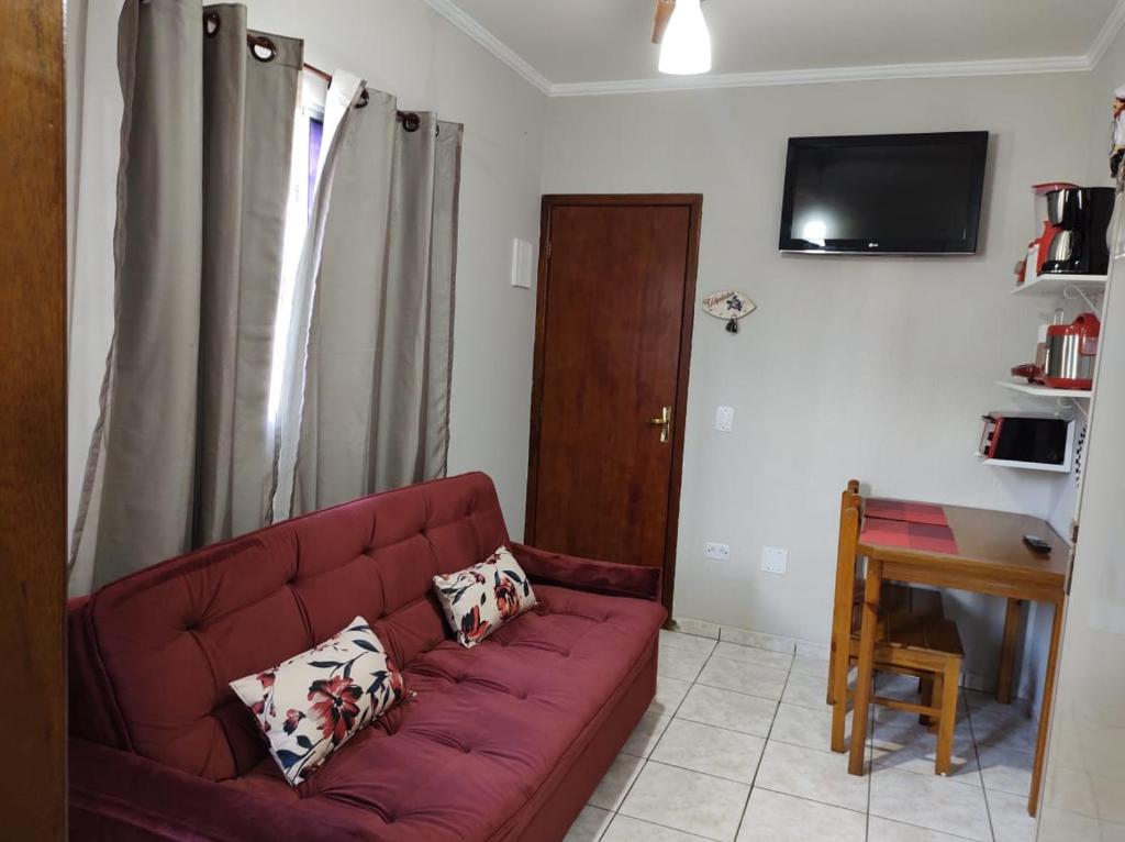 a living room with a red couch and a table at Apartamento Ubatuba - Praia grande - 260m da praia in Ubatuba