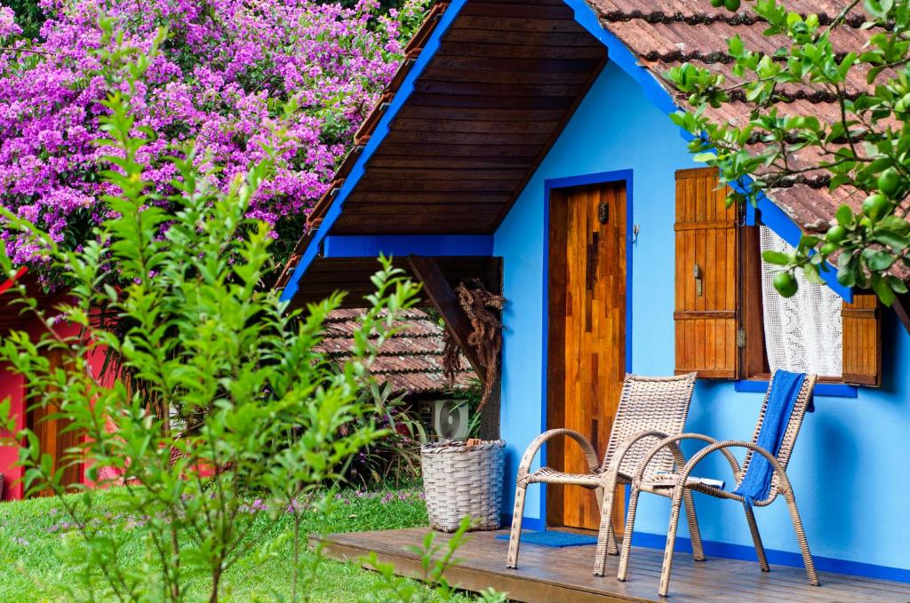 a blue house with two chairs and flowers at Pousada Colher de Chá in Visconde De Maua